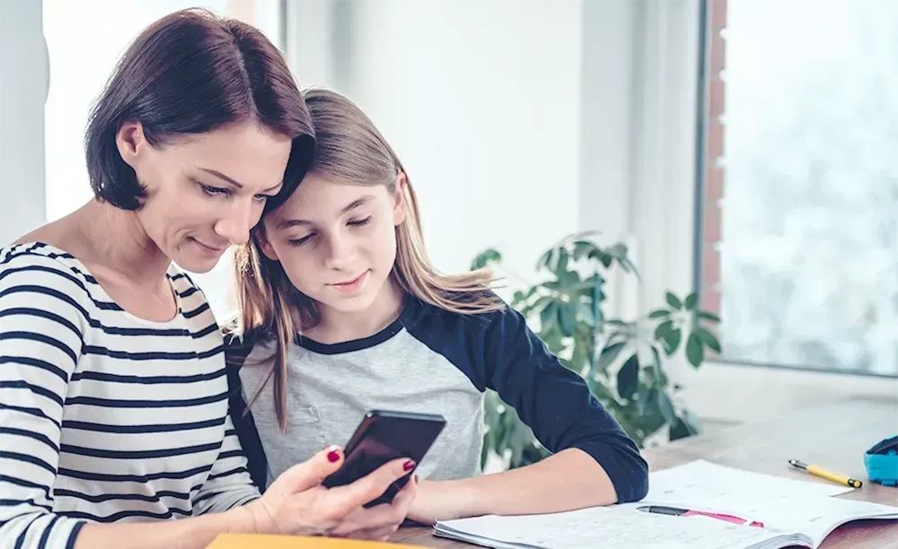 Madre e hija buscando información en su smartphone sobre clases de inglés en Panamá